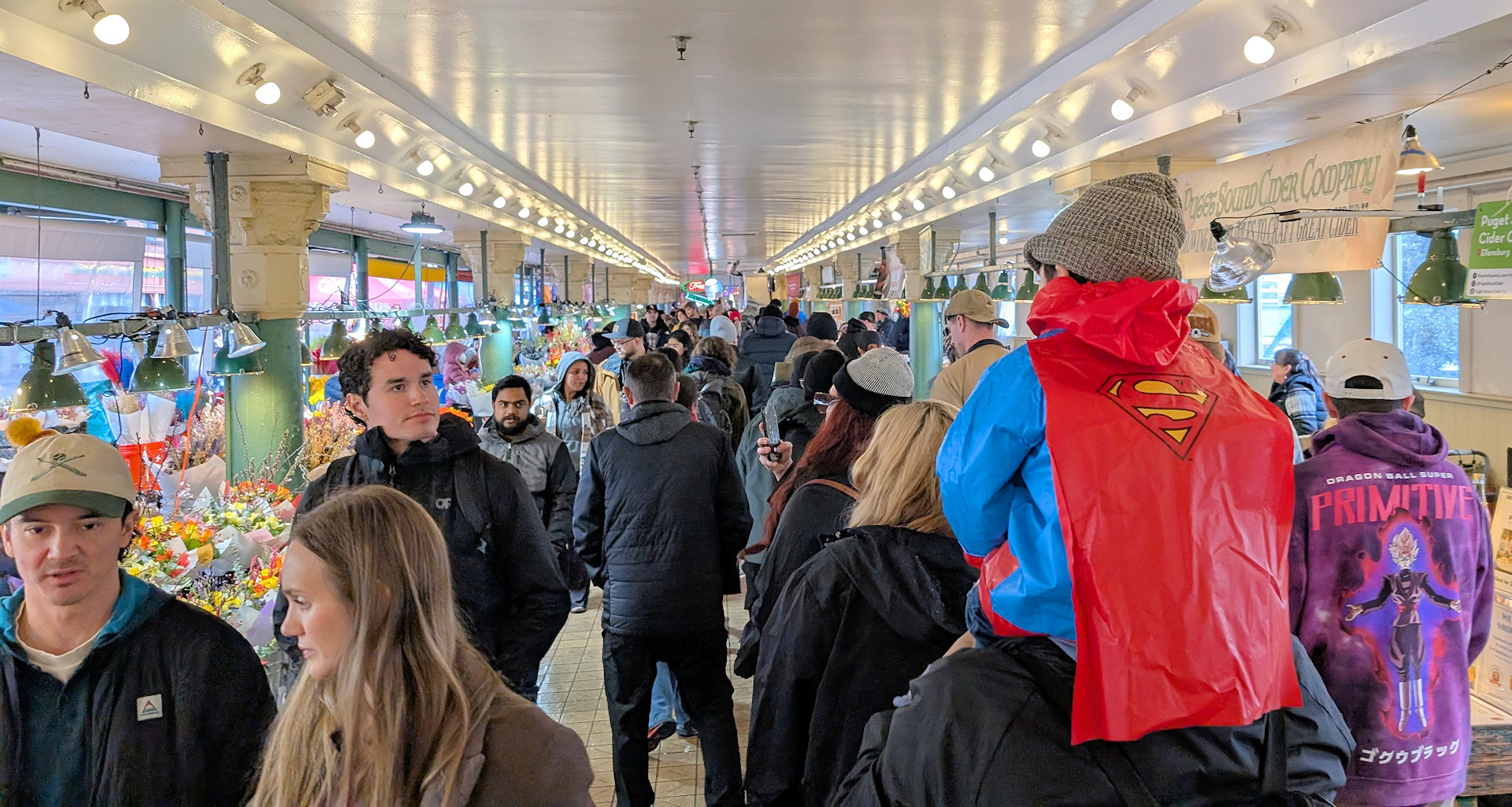 Kleiner als Superman verkleideter Junge auf den Schultern seines Vaters im Menschen Gedränge