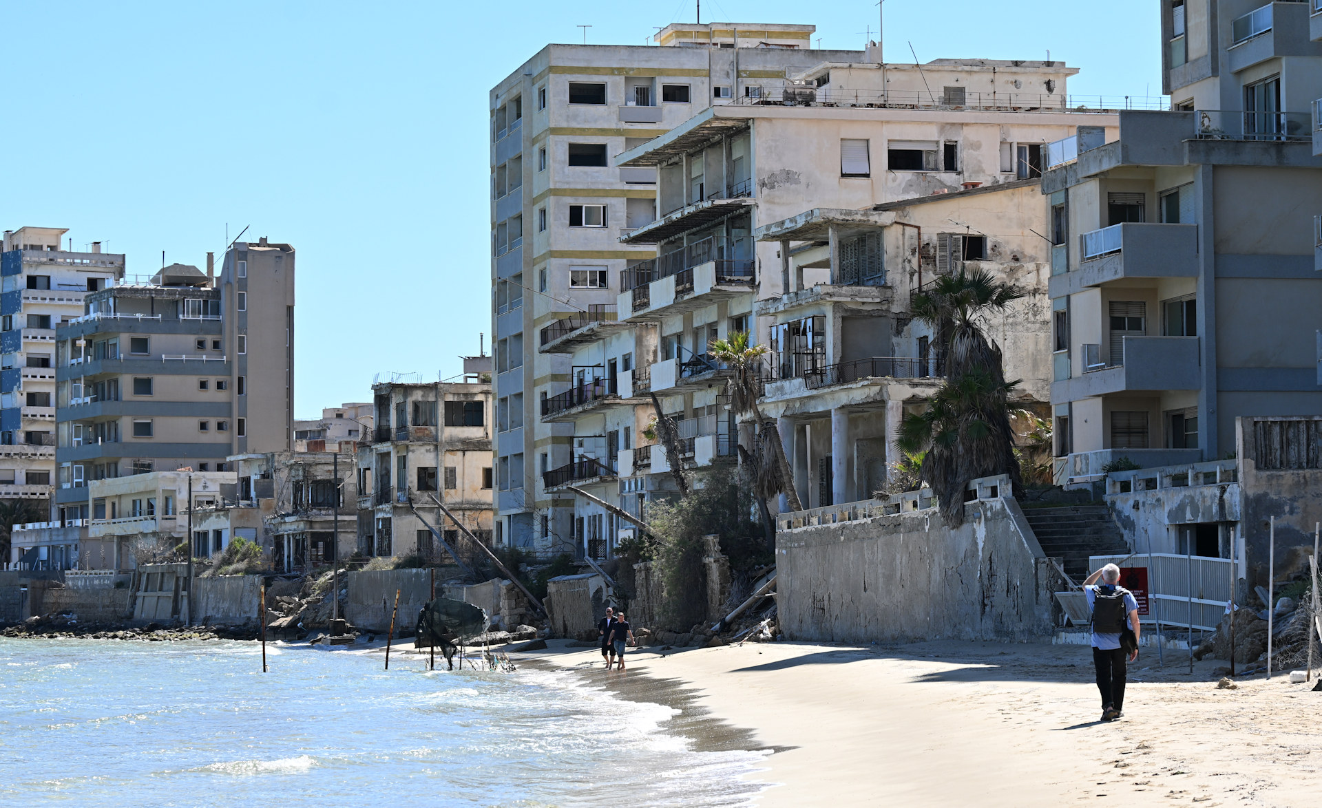 Drei Spaziergänger am Strand von Varosha vor Hotel Ruinen