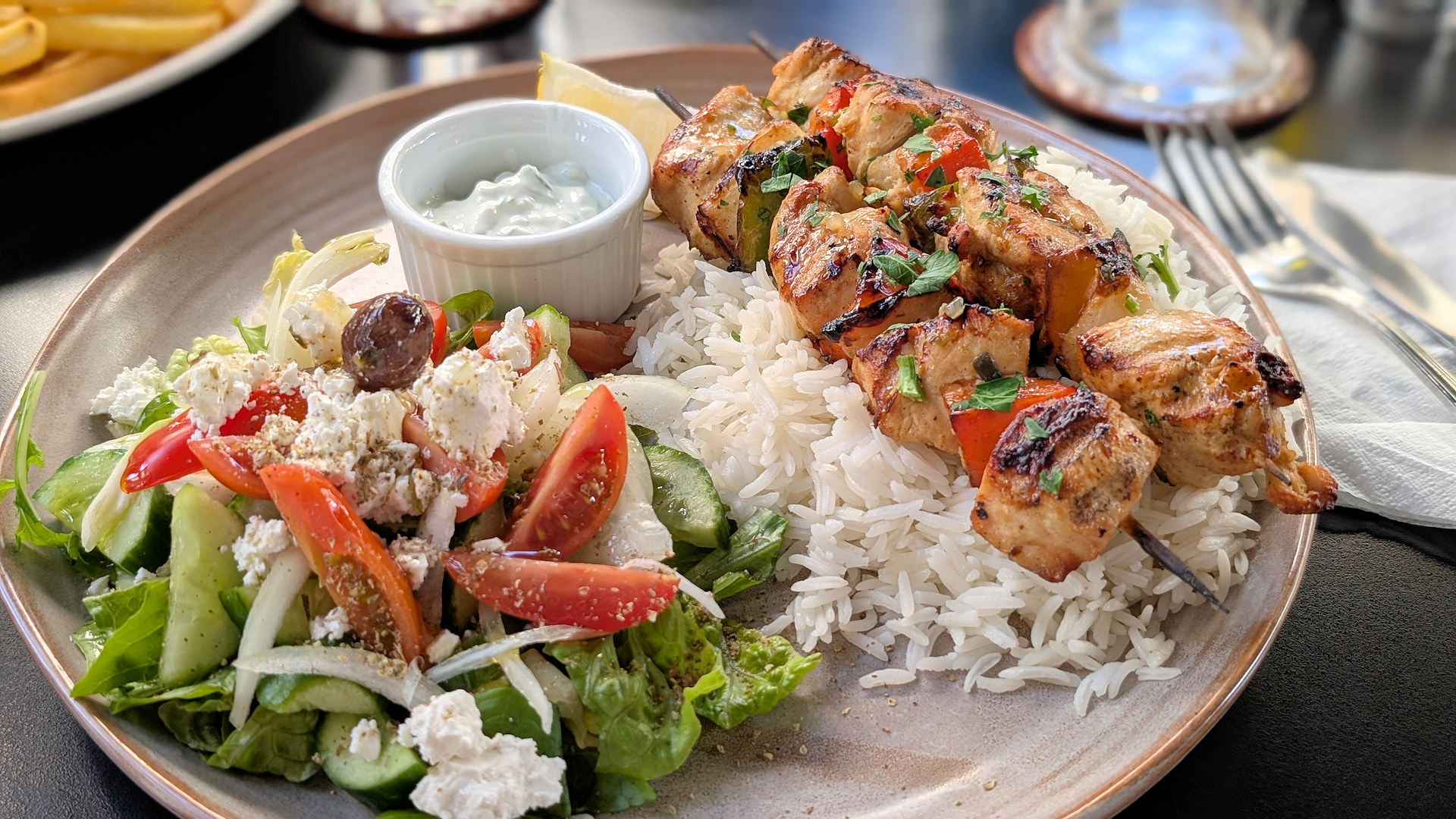 Eine Portion Salat mit Tomaten, weisser Reis und zwei lecker aussehende Hähnchen Spiesse 