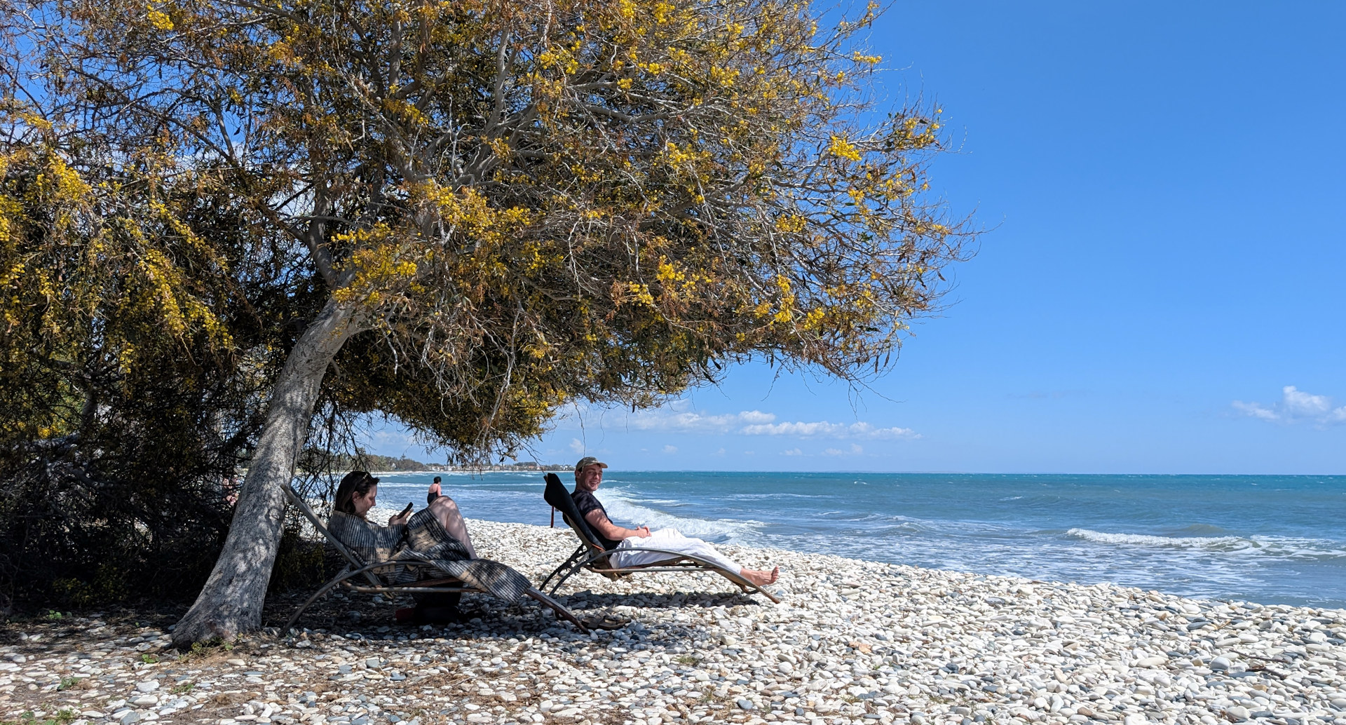 Zwei Jugendluche sitze in Zypern im Schatten am Kiesel Strand am Meer 