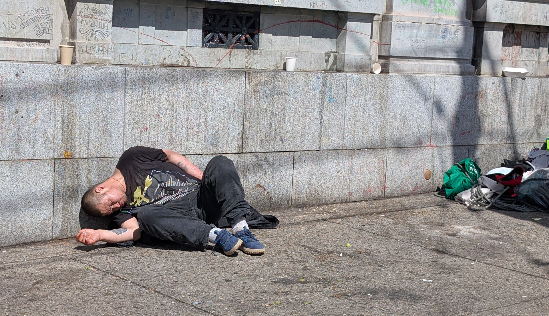 Drogenabhängiger Mann schläft in East Hastings Vancouver an eine Häuserwand gelehnt