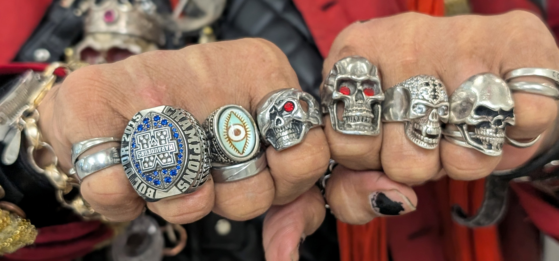 Hand mit mehreren silbernen Totenkopf Ringen an den Händen