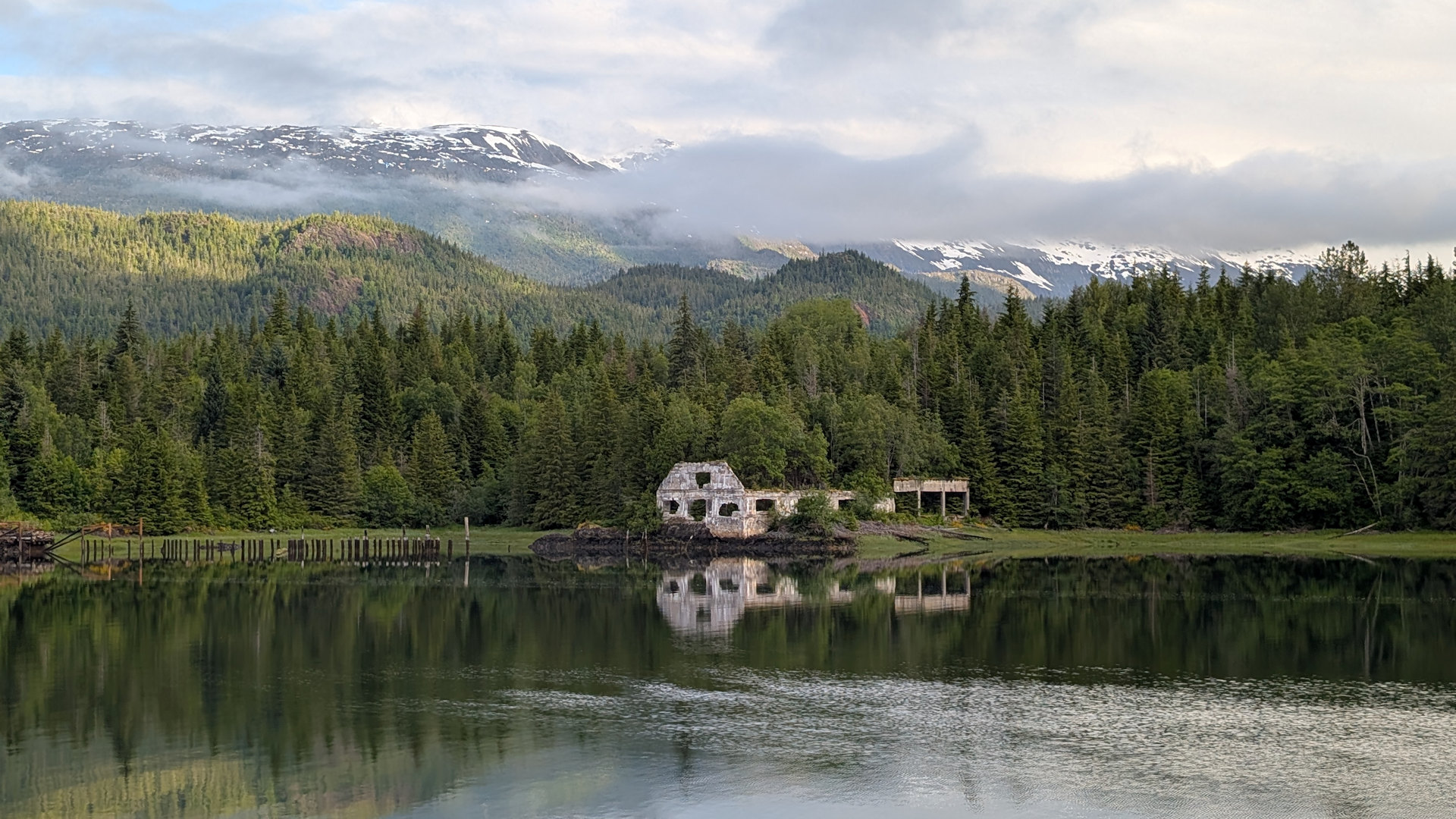 Ruine eines Hauses in Anyox aus dem Bäume wachsen mit Bergen und Wolken im Hintergrund