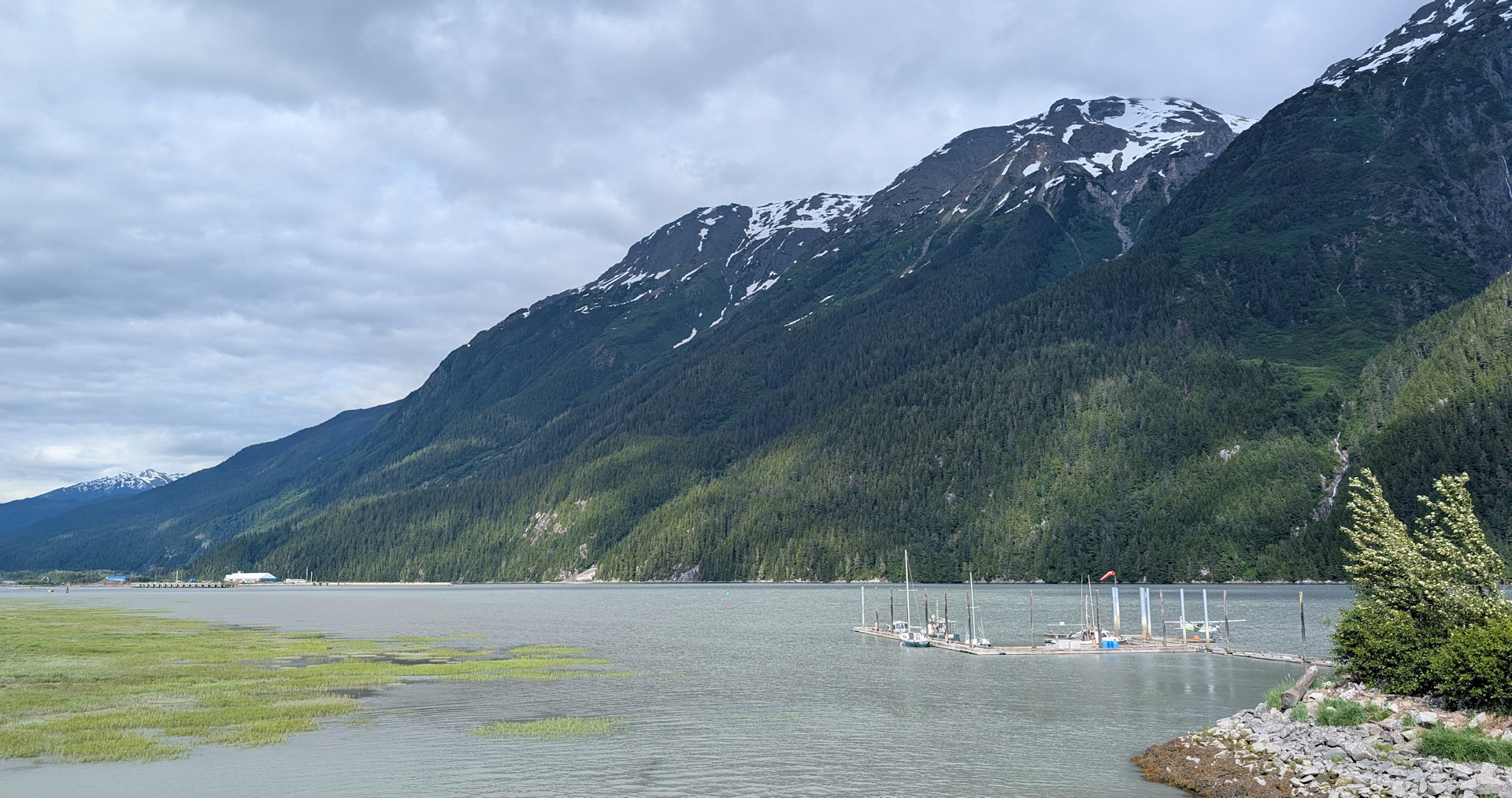Hafen von Hyder Alaska mit Segelbooten und einem Wasserflugzeug, umgeben von schneebedeckten Bergen 