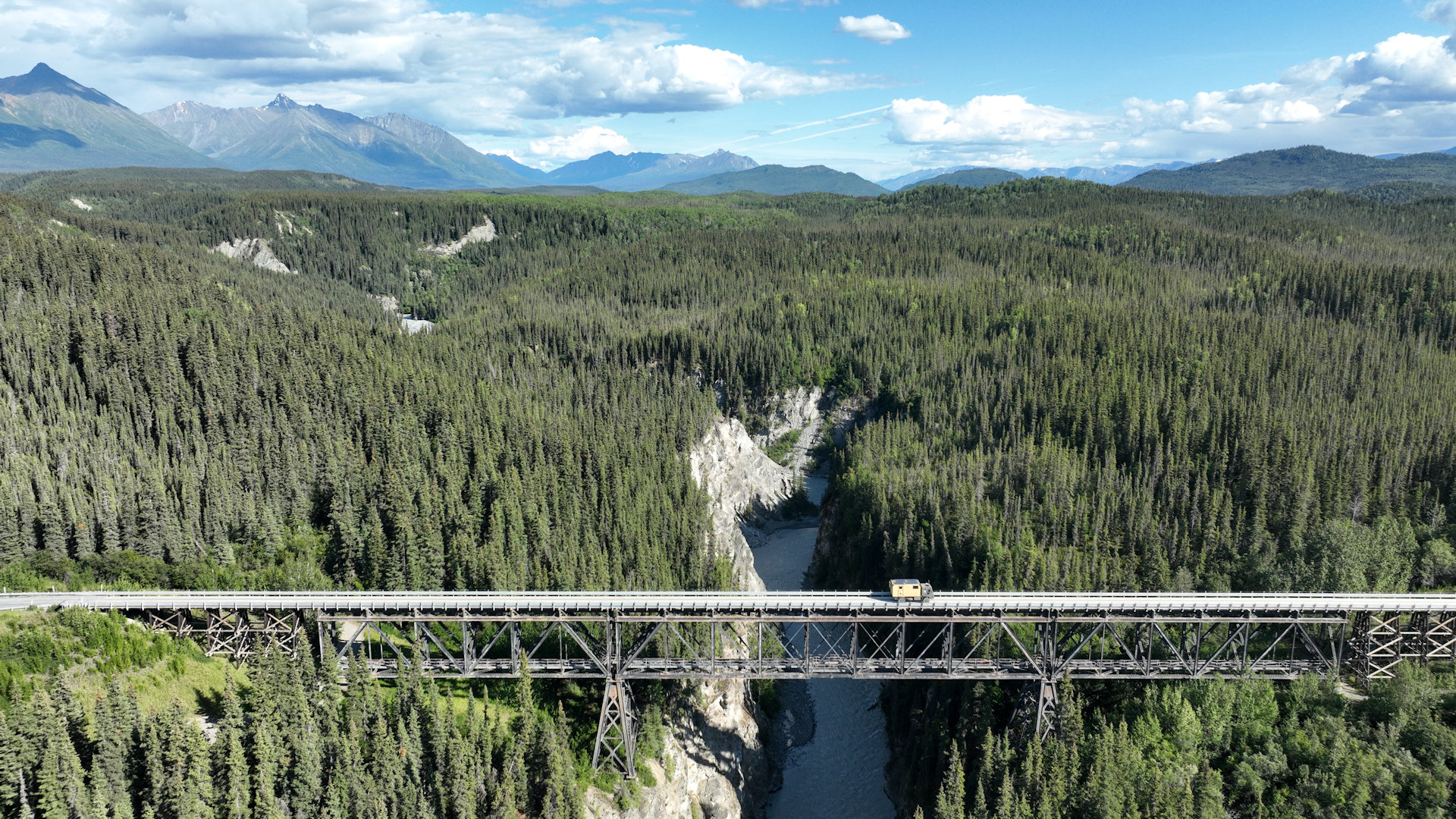 LKW fährt in Alaska über eine lang gezogene Brücke mit tiefer Schlucht