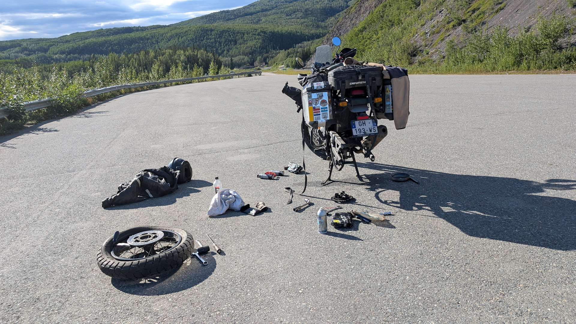 Motorrad mit demontiertem Hinterrad und verstreuten Einzelteilen auf einem Parkplatz in Alaska
