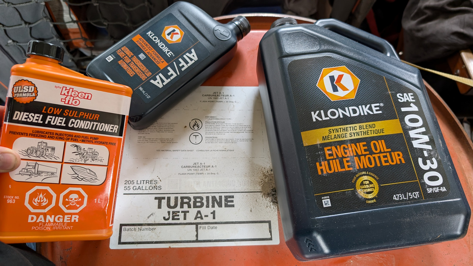 Orangenes Jet-A Fass und drei Plastikflaschen mit Diesel Zusätzen um das Kerosin im DAF T244 zu verwenden