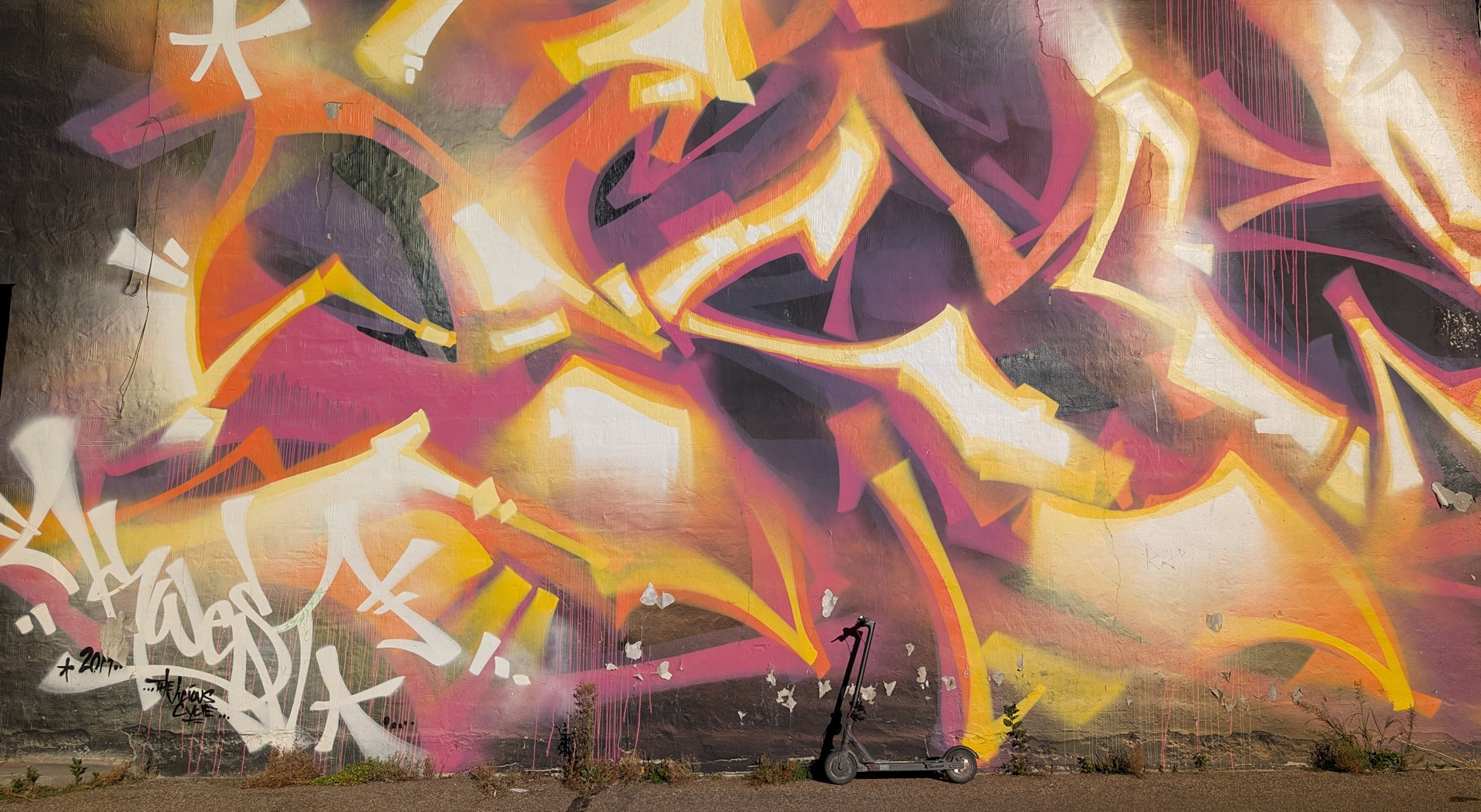 Abstraktes Graffiti Kunstwerk in Edmonton in gelb weiss und lila mit einem zum Grössenvergleich davor parkenden eScooter 