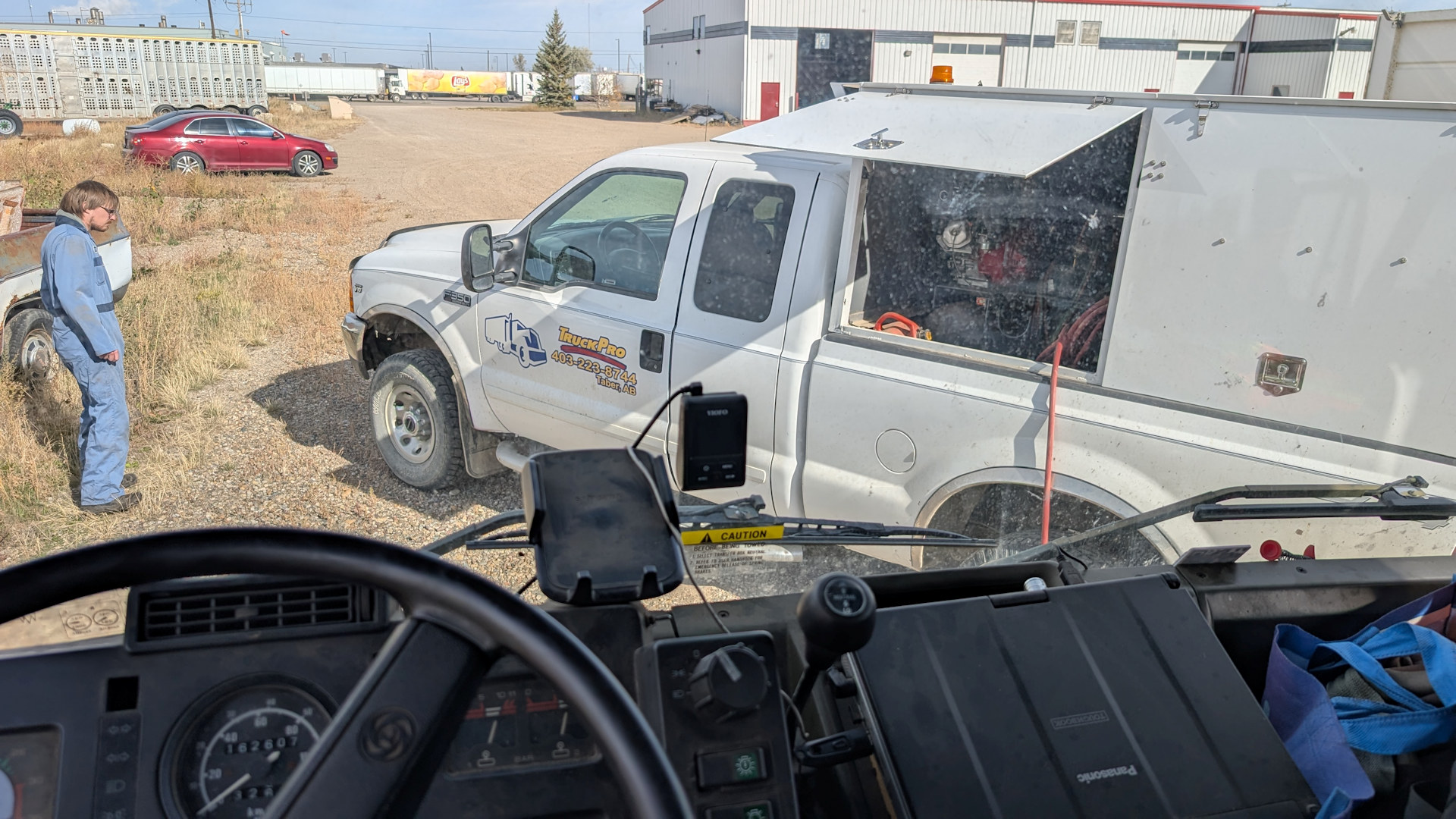 Blick aus dem Cockpit vom DAF T244 auf einen davor parkenden weissen Ford Service Wagen zum Abschleppen