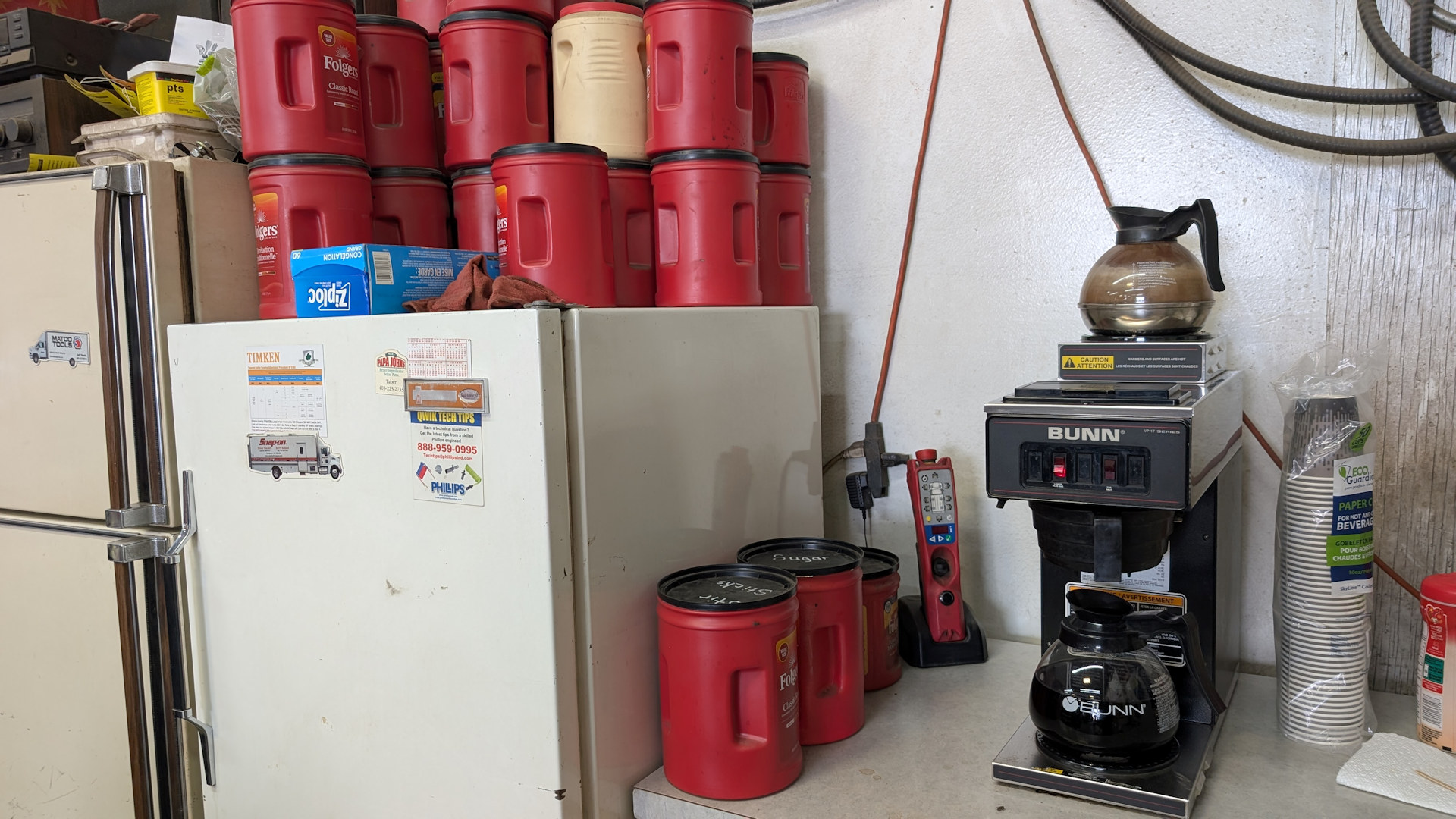 Immenser Vorrat roter Behälter mit Kaffee Pulver neben einer Kaffee Maschine in einer Werkstatt