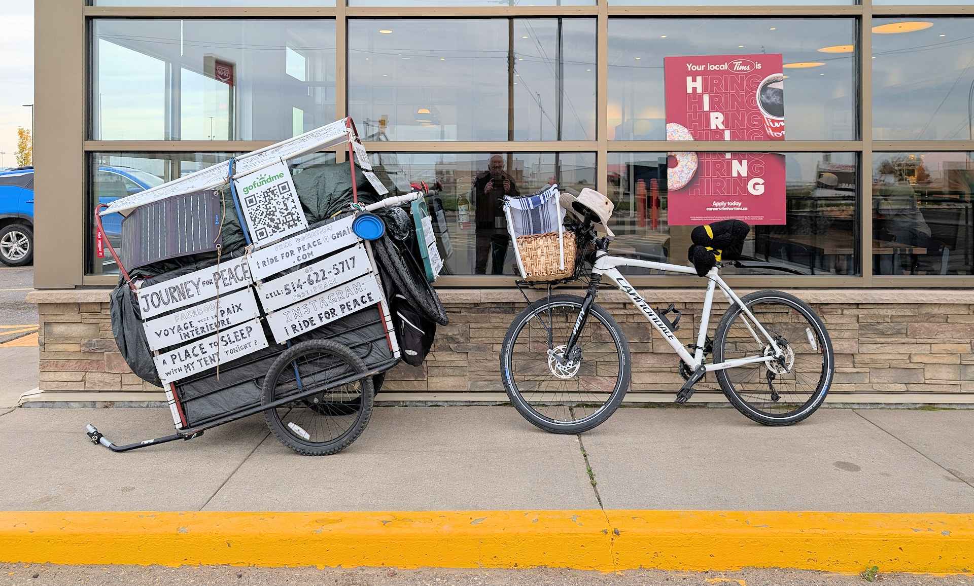 Fahrrad mit Anhänger von einem Obdachlosen vor einer Tim Hortons Filiale in der mit einem Plakat im Fenster nach Arbeitskräften gesucht wird