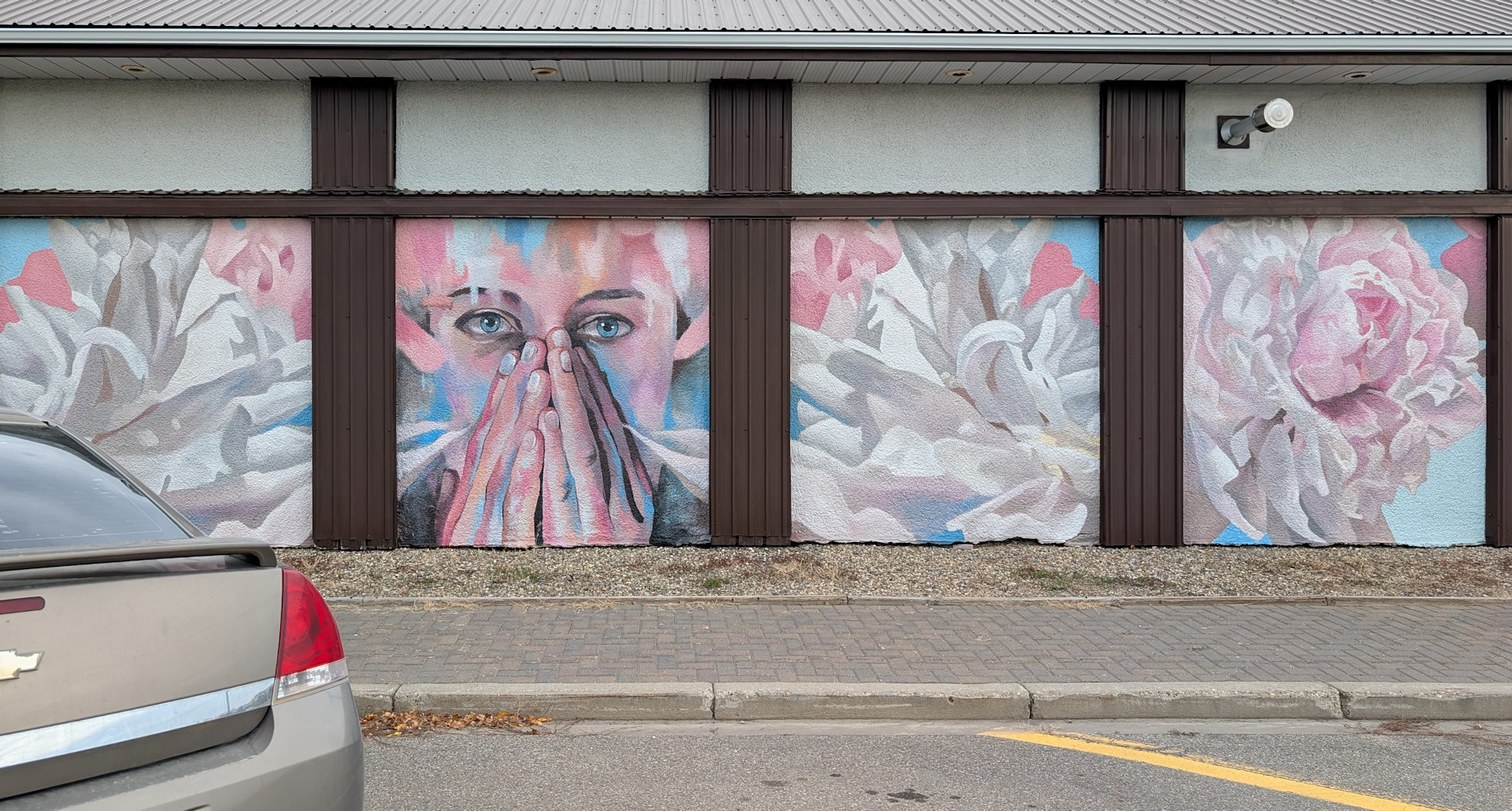 Strassenkunst in Taber. Innerbloom von Dave Thomas, zeigt eine Frau und weisse Frühlingsblumen.
