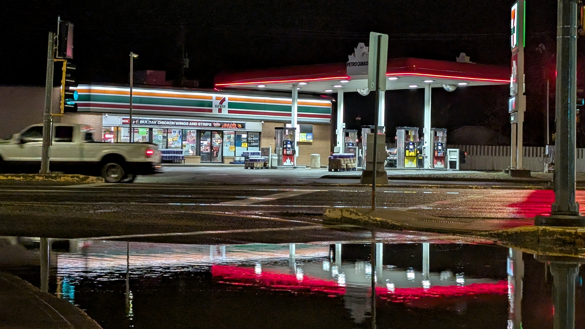 Rot leuchtende Tankstelle und 711 in Taber, die sich in einer Pfütze spiegeln